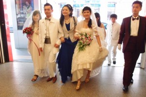 With brides and grooms in hand, Hellen happily strides into the wedding reception area.